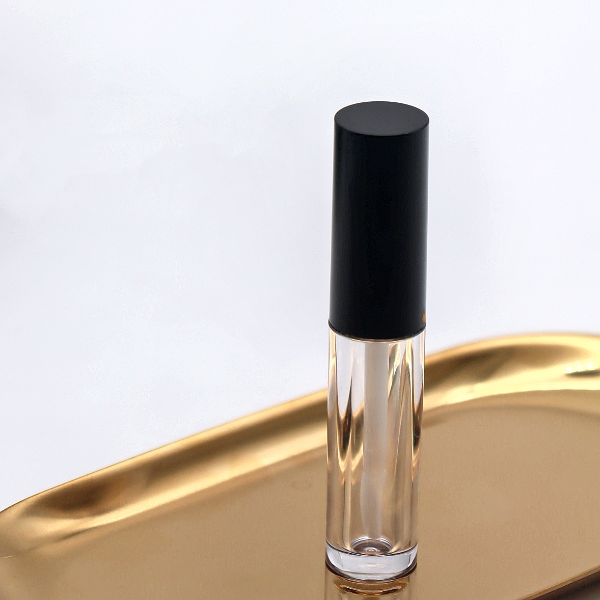 Clear Empty Lip Gloss Bottle with Applicator Wand on Gold Metal Tray Cosmetic Packaging IVANS